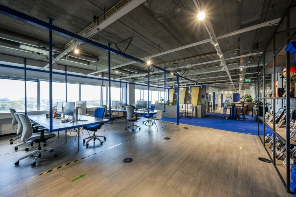 Modern kantoorinterieur aan de Johan Huizingalaan met open werkplekken, industriële plafonds en veel daglicht.